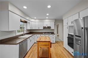 kitchen featuring dark countertops, stainless steel appliances, white cabinetry, and under cabinet range hood