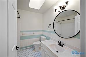 full bathroom featuring toilet, a skylight, a shower, and vanity