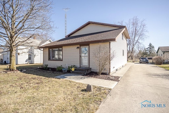 bungalow-style home featuring a front yard, driveway, and roof with shingles