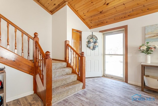foyer entrance featuring stairs, baseboards, wooden ceiling, wood finished floors, and vaulted ceiling
