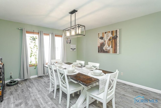dining room with light wood-style floors, baseboards, and an inviting chandelier