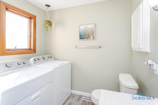 bathroom with visible vents, wood finished floors, washer and dryer, toilet, and baseboards