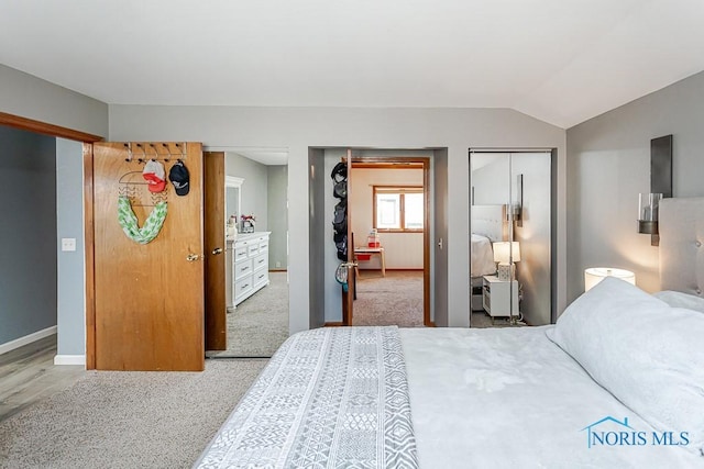 carpeted bedroom with baseboards, multiple closets, and vaulted ceiling