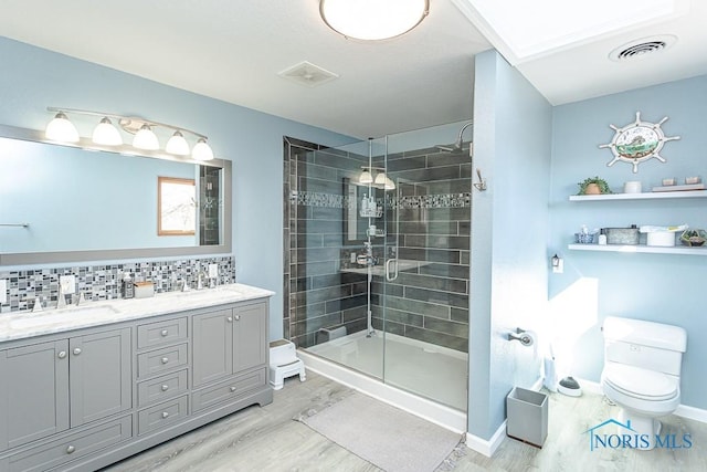 full bath featuring visible vents, a stall shower, wood finished floors, a sink, and toilet