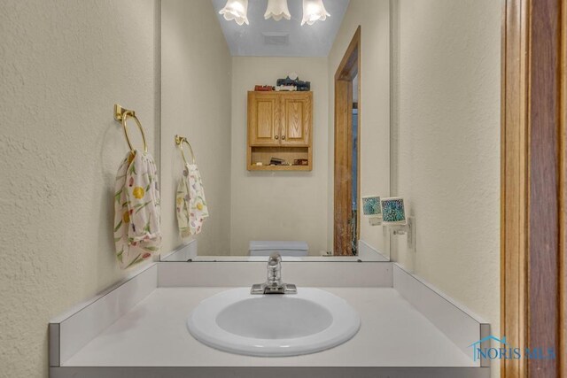 3739 Wild Pheasant Ln, Sylvania, OH 43560 - bathroom featuring a textured wall, a chandelier, vanity, and toilet