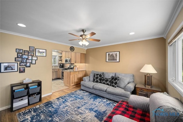 living area with light wood-style floors, ornamental molding, ceiling fan, and a wealth of natural light