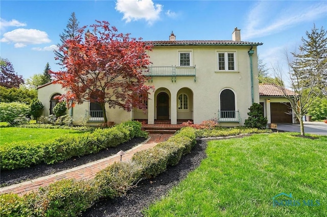 3405 Chestnut Hill Rd, Ottawa Hills, OH 43606 - mediterranean / spanish-style home with a chimney, a balcony, a front yard, stucco siding, and a tile roof