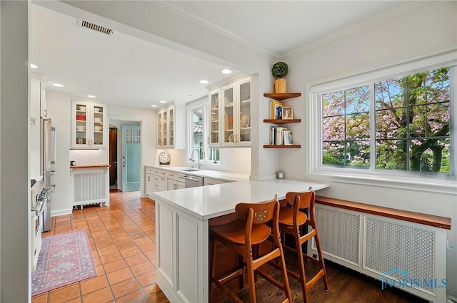3405 Chestnut Hill Rd, Ottawa Hills, OH 43606 - kitchen with radiator heating unit, decorative backsplash, a peninsula, light countertops, and white cabinetry