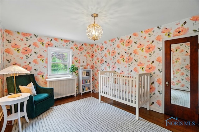 3405 Chestnut Hill Rd, Ottawa Hills, OH 43606 - bedroom with wallpapered walls, radiator, wood finished floors, a chandelier, and a crib