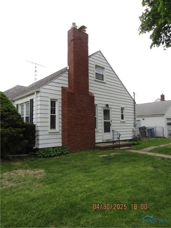rear view of property with a yard and a chimney