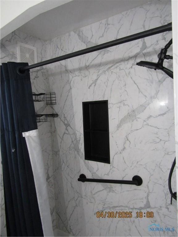full bath featuring visible vents and a marble finish shower