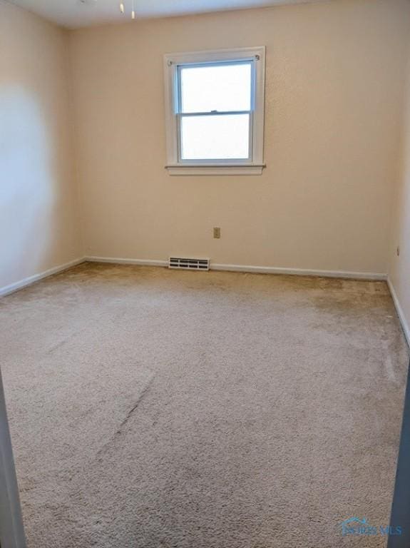 spare room with visible vents, baseboards, and carpet floors