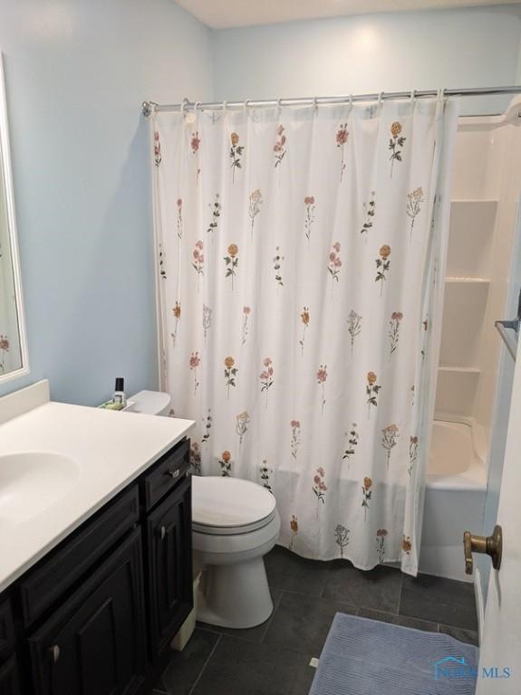 full bath featuring tile patterned floors, vanity, toilet, and shower / bath combination with curtain