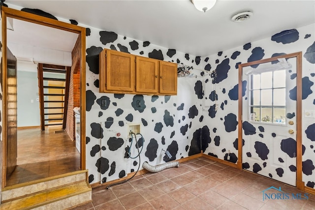 interior space featuring tile patterned floors, brown cabinetry, wallpapered walls, and visible vents