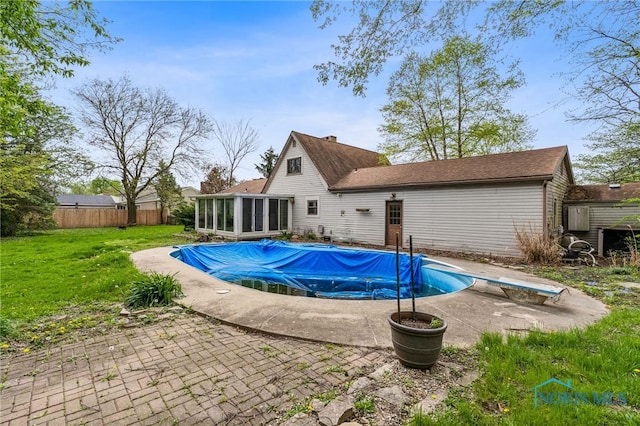 view of swimming pool with a patio area, a sunroom, fence, a fenced in pool, and a yard