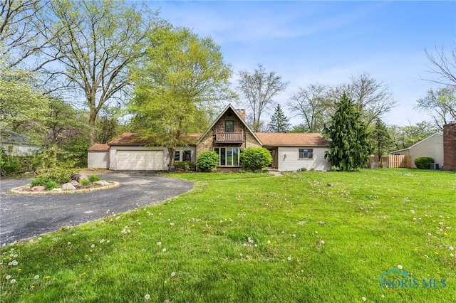 view of front of house featuring a chimney, an attached garage, driveway, and a front yard