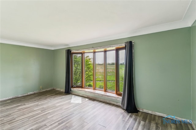 empty room featuring crown molding, baseboards, visible vents, and wood finished floors