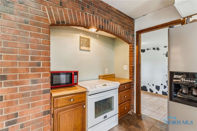 kitchen with brown cabinetry, white electric range oven, dark tile patterned floors, fridge with ice dispenser, and wood counters
