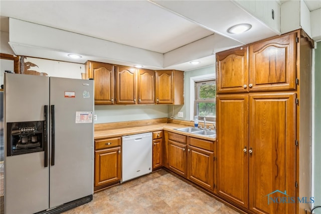 kitchen featuring a sink, brown cabinets, stainless steel refrigerator with ice dispenser, and dishwasher