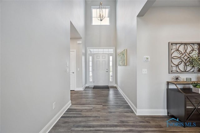 foyer with baseboards, a high ceiling, dark wood-style floors, and a notable chandelier