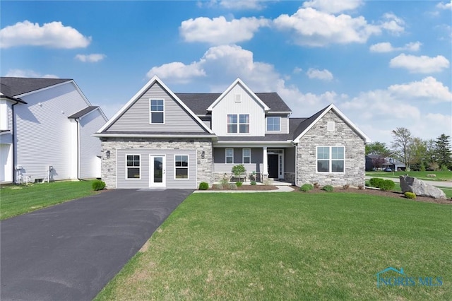 craftsman house with board and batten siding, a front yard, driveway, and stone siding