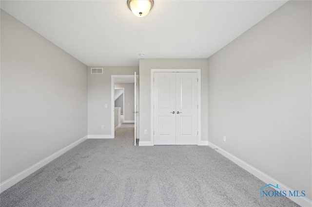 unfurnished bedroom with baseboards, carpet flooring, visible vents, and a closet