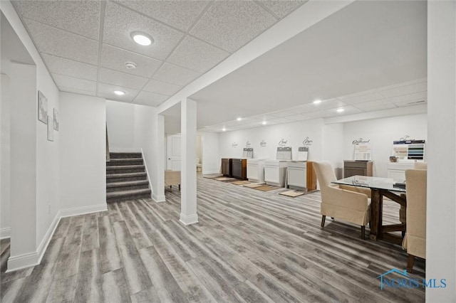 finished basement featuring a paneled ceiling, washer / clothes dryer, wood finished floors, and stairway