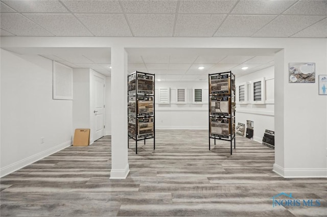 finished basement featuring wood finished floors, a fireplace, baseboards, recessed lighting, and a paneled ceiling
