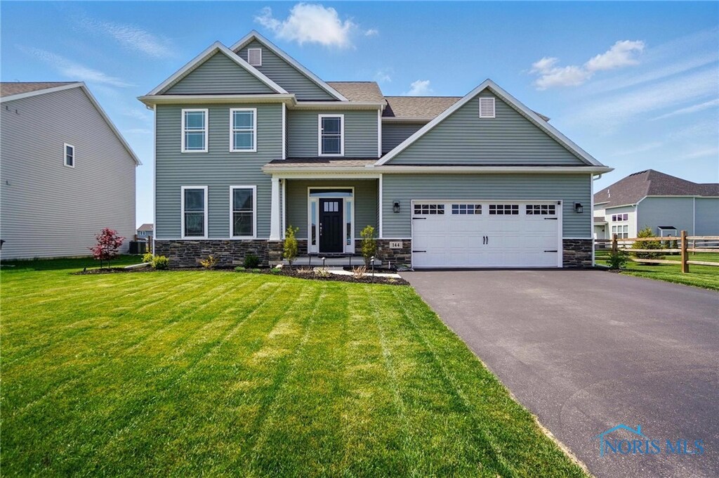 144 Bentley Dr, Perrysburg, OH 43551 - craftsman-style house with fence, a front yard, stone siding, an attached garage, and driveway