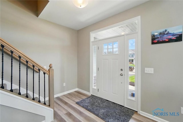 foyer with stairs, baseboards, and wood finished floors