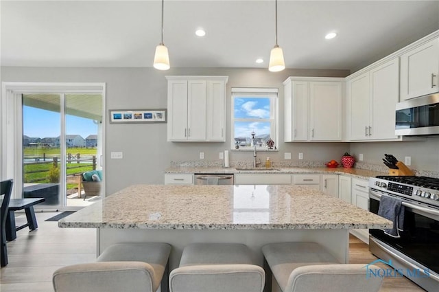 kitchen featuring pendant lighting, a breakfast bar area, white cabinets, a sink, and stainless steel appliances