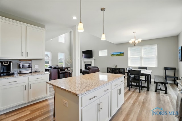 kitchen with a healthy amount of sunlight, white cabinets, a fireplace, and light wood finished floors