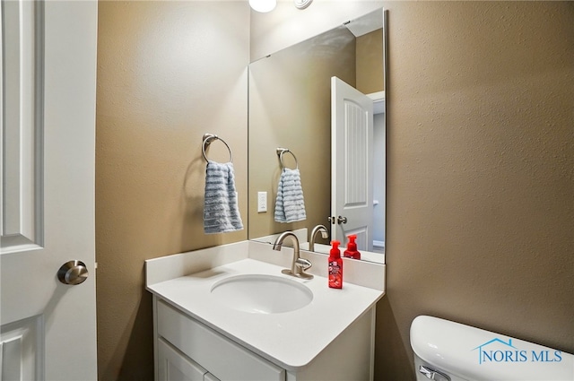 half bathroom with vanity and toilet