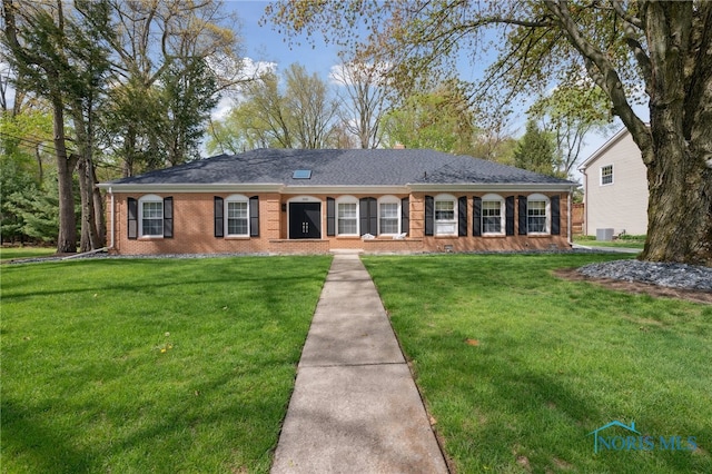 ranch-style house featuring brick siding, central AC, and a front yard