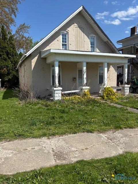 bungalow-style house featuring covered porch, brick siding, and a front lawn