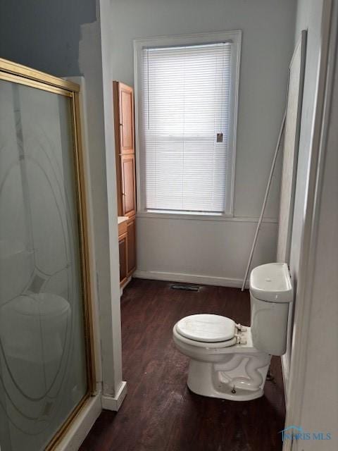 bathroom featuring wood finished floors, baseboards, a stall shower, and toilet