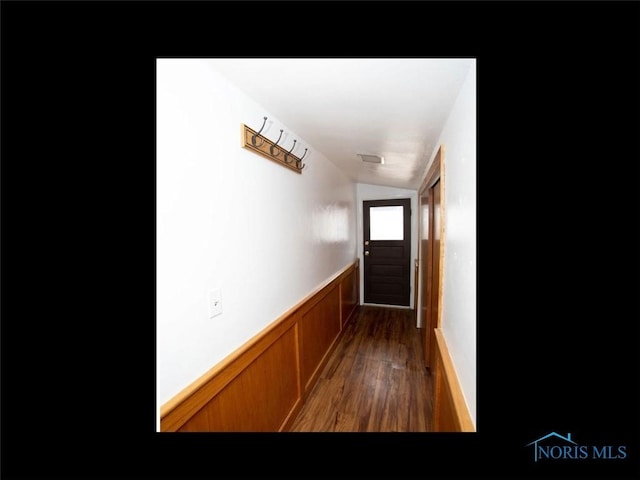 doorway to outside with wood finished floors, lofted ceiling, and a wainscoted wall