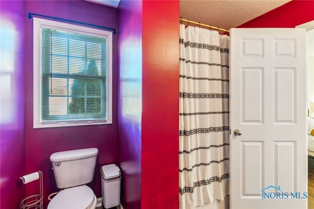 full bathroom featuring a textured ceiling, toilet, and a shower with curtain