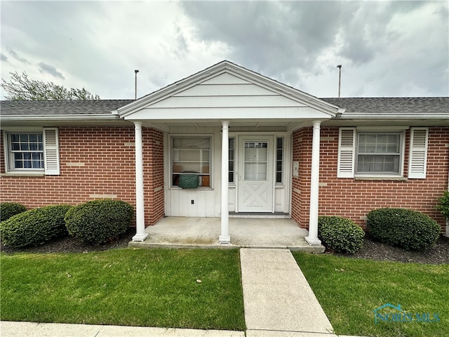 716 N Union St Unit B, Fostoria, OH 44830 - view of front of house with covered porch, a shingled roof, a front lawn, and brick siding