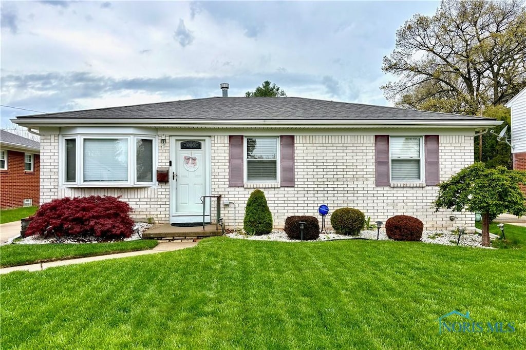 view of front of home with brick siding and a front lawn