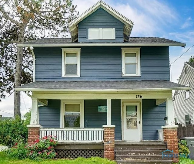 american foursquare style home featuring a porch, a shingled roof, and central air condition unit
