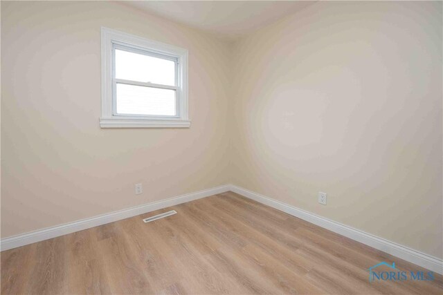 unfurnished room featuring baseboards, light wood-style flooring, and visible vents