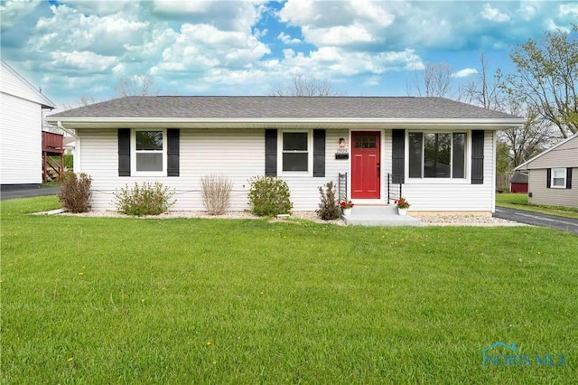 ranch-style house featuring a shingled roof and a front lawn