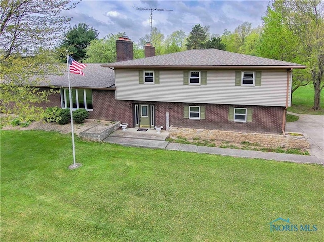 back of property with a chimney, a yard, and brick siding