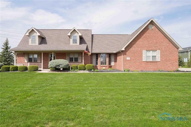 cape cod-style house featuring brick siding, a front lawn, roof with shingles, and a porch