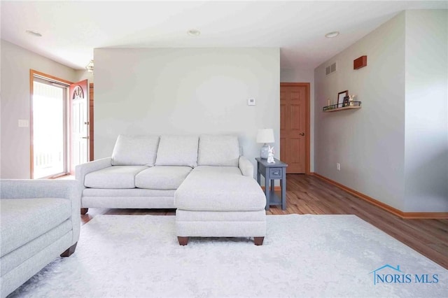 living room featuring baseboards, visible vents, and wood finished floors