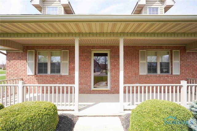property entrance featuring brick siding and covered porch