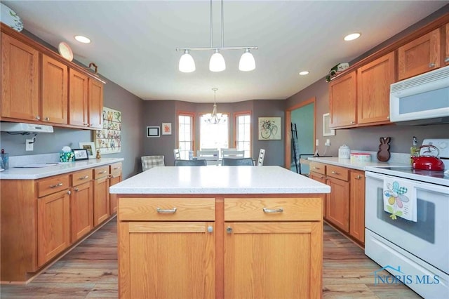 kitchen featuring white appliances, light countertops, light wood-style floors, and a center island