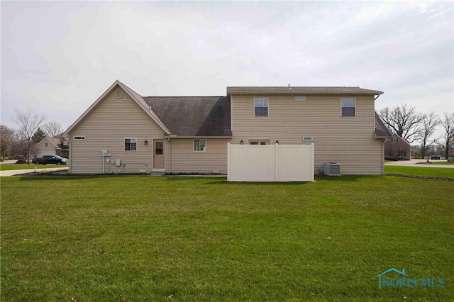 rear view of house with a yard and cooling unit