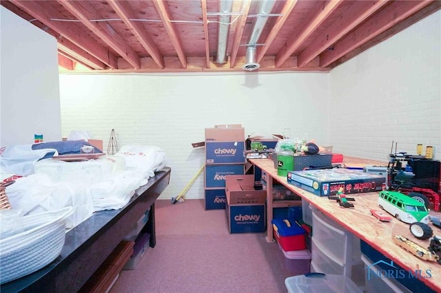interior space featuring a workshop area, carpet, and brick wall